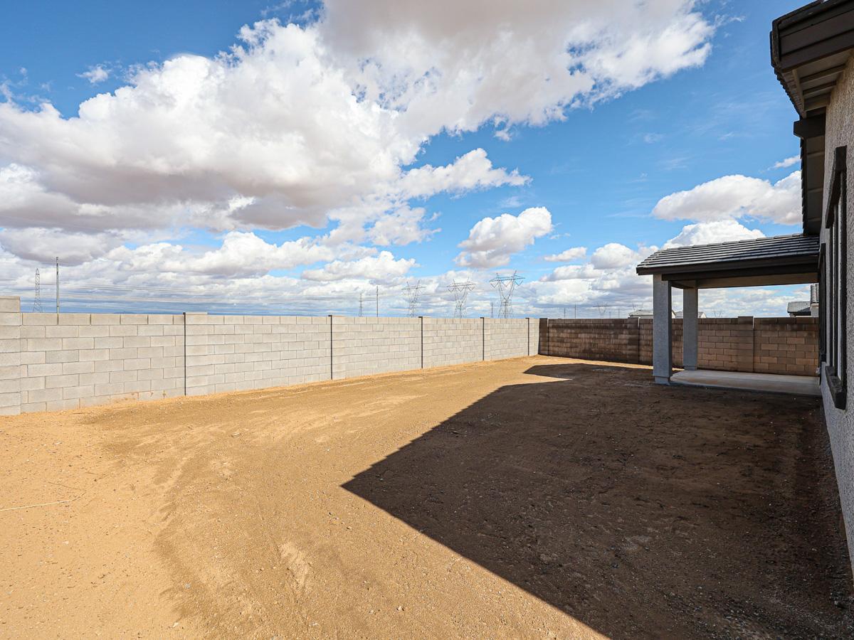 A dirt road with a fence and a beach in the background.