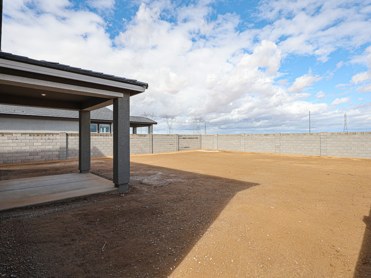 A sandy area with a fence and a building in the background.