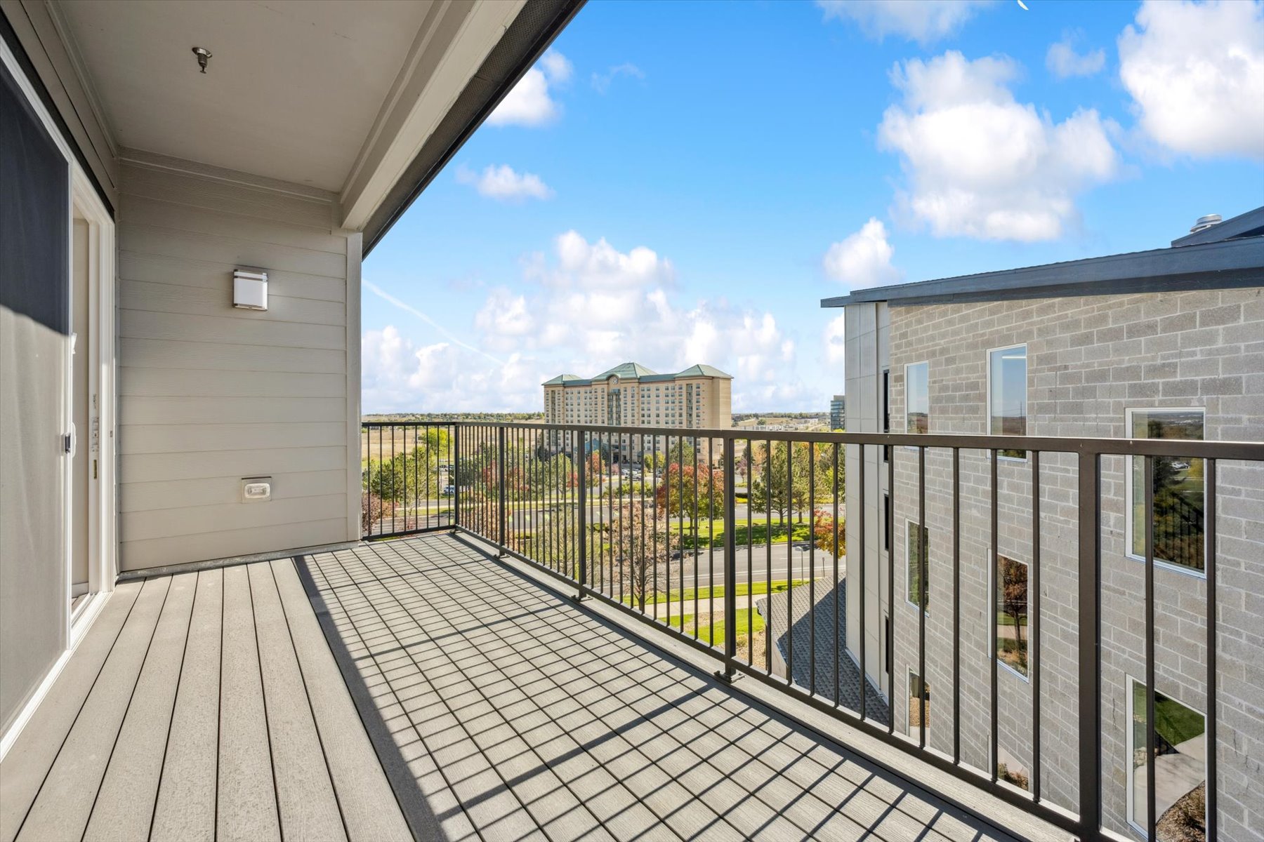 A deck with a fence and a building in the background.