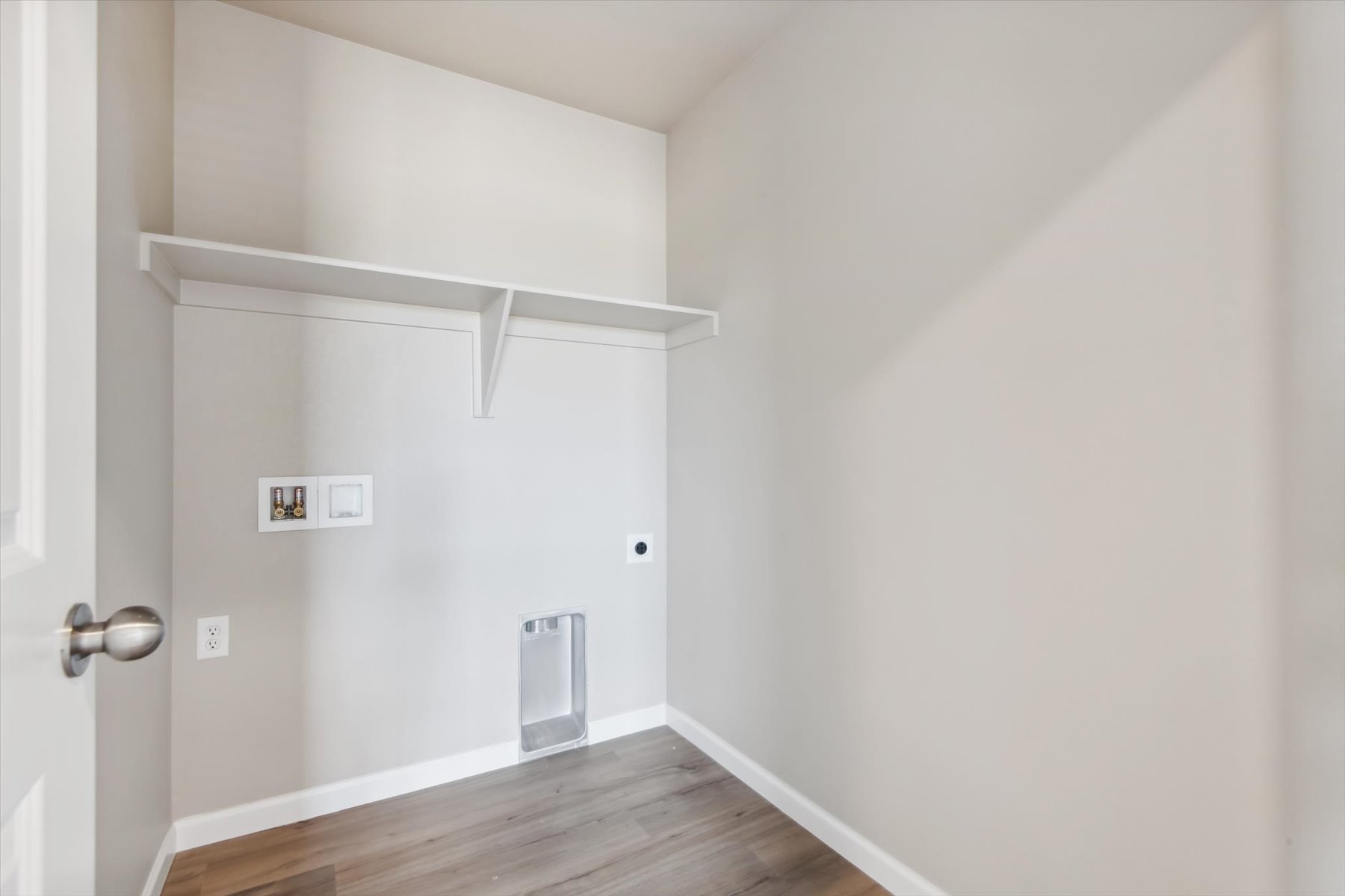 A white room with a wood floor and a white wall.