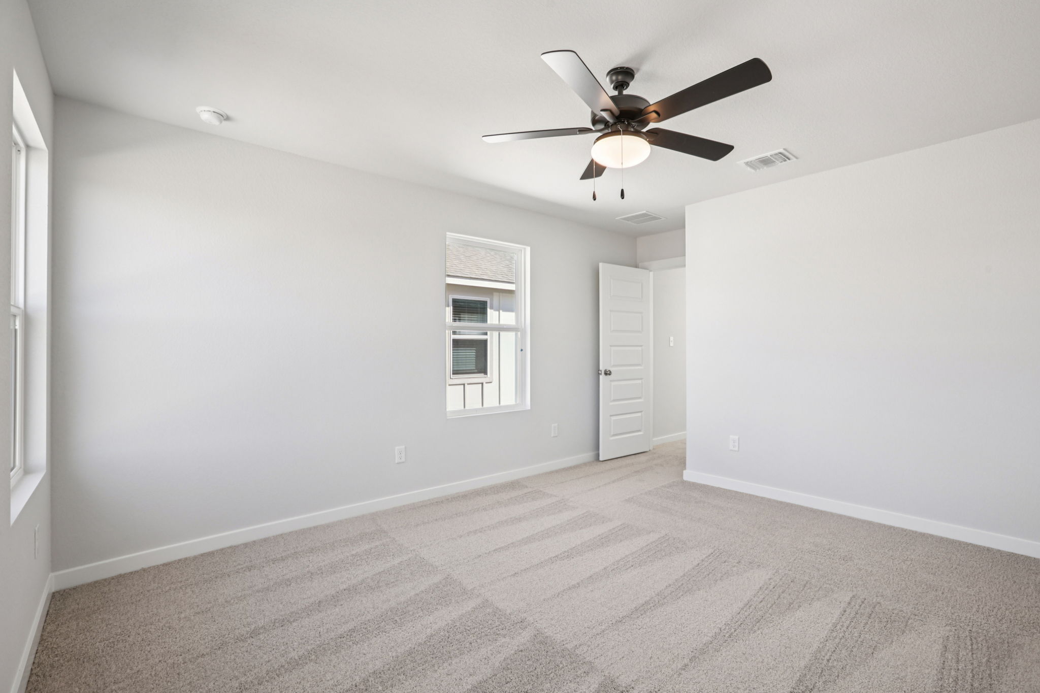 A room with a ceiling fan and a door.