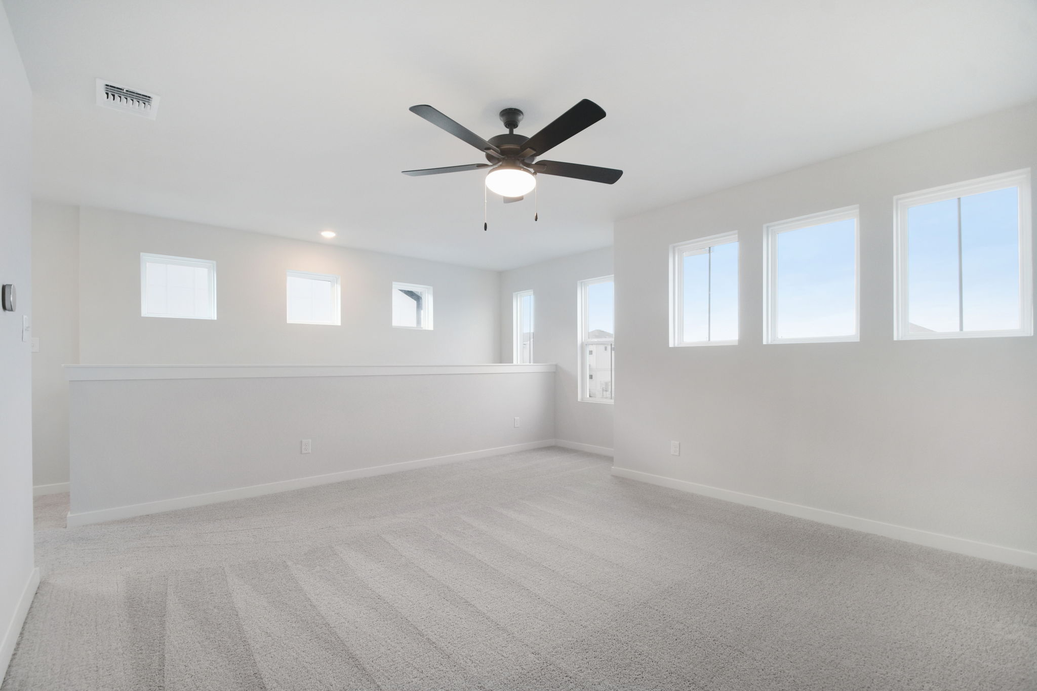 A room with a ceiling fan and windows.