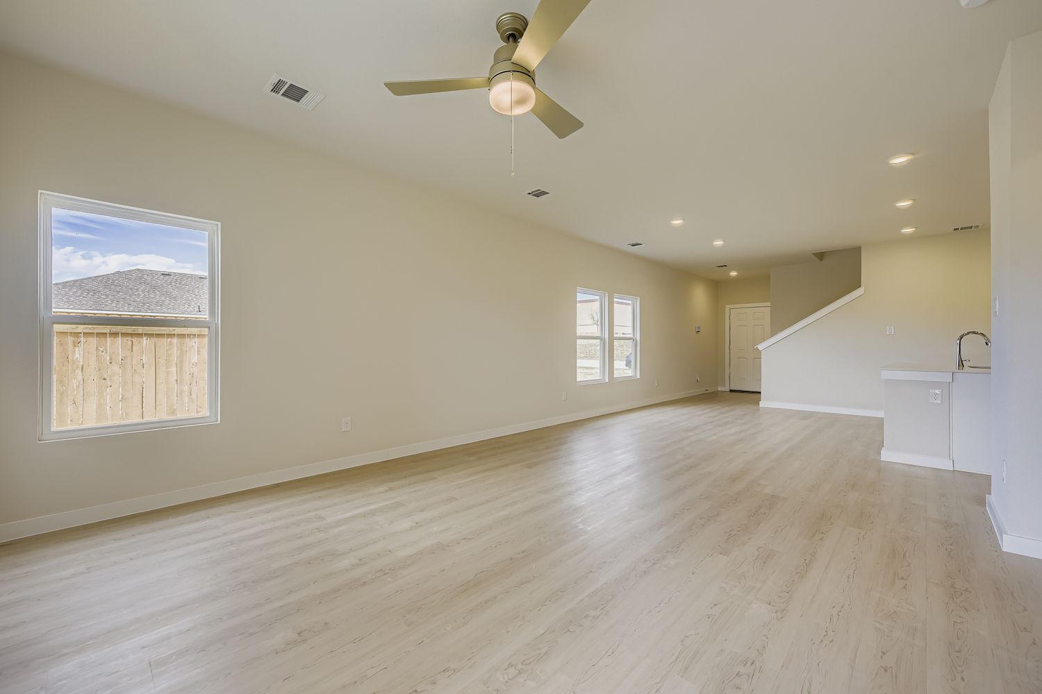 A large empty room with a wood floor and a ceiling fan.