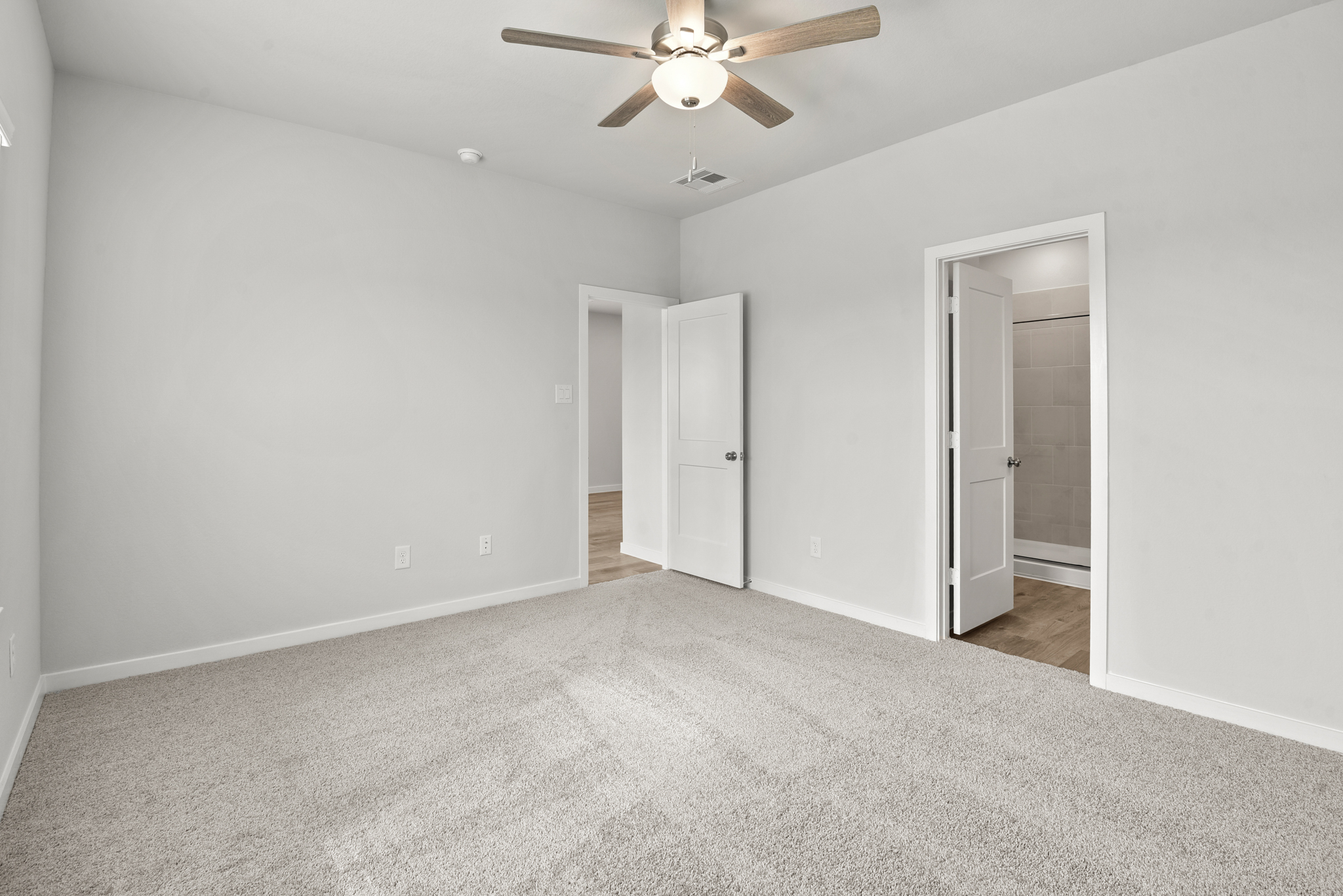 A room with a ceiling fan and a door.