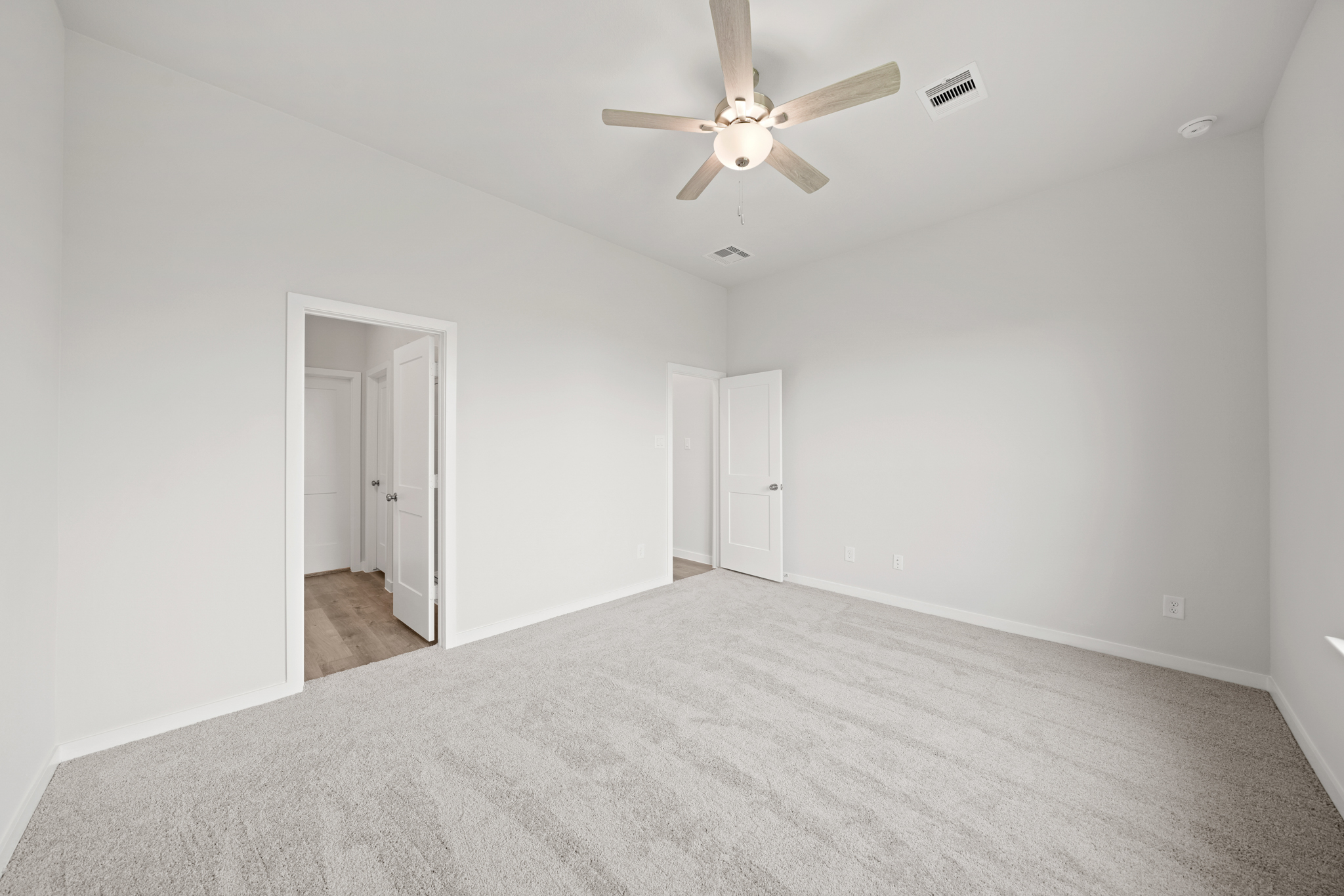A room with a ceiling fan and white walls.