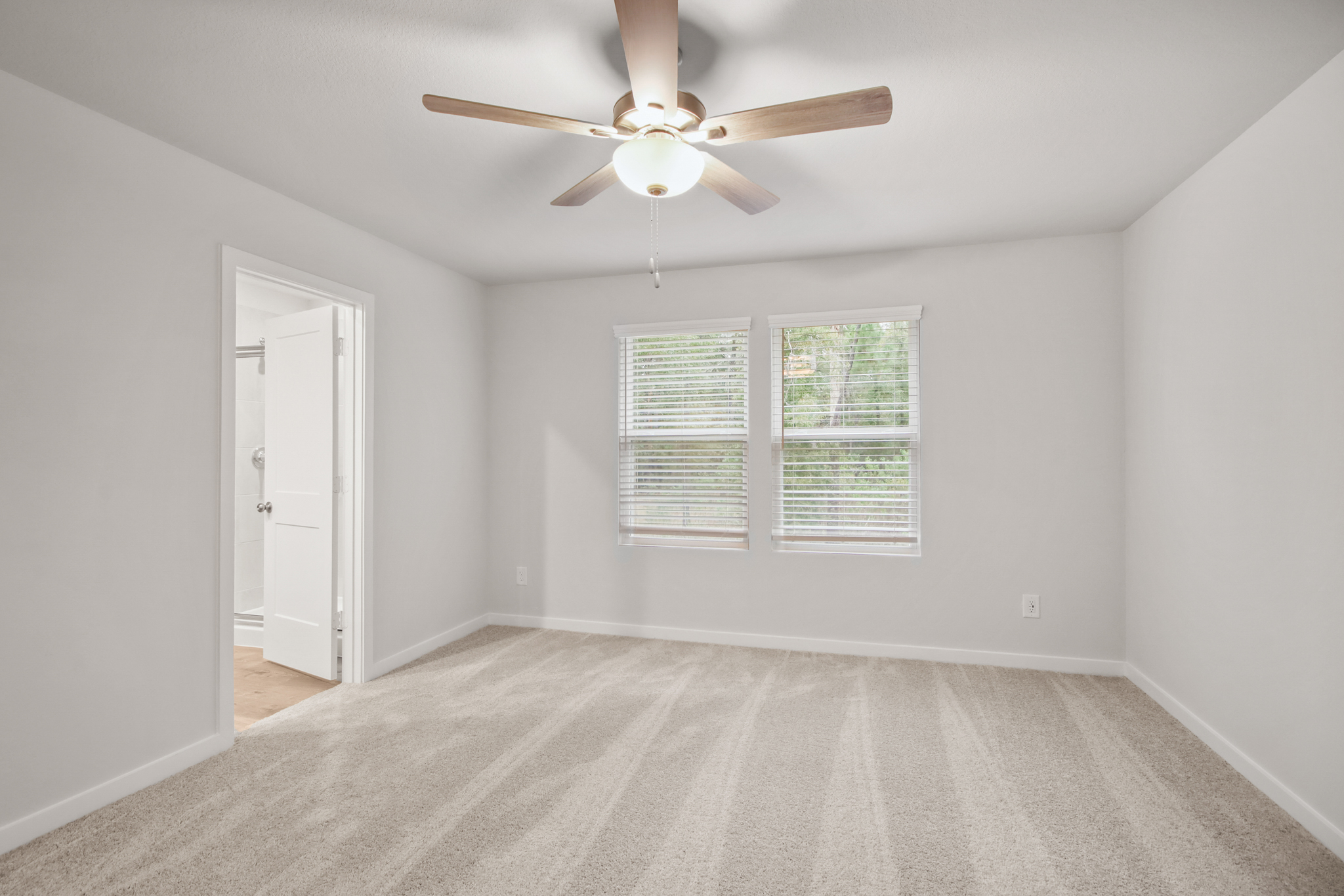 A room with a ceiling fan and a door.