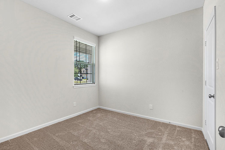 A room with a carpet and a window.