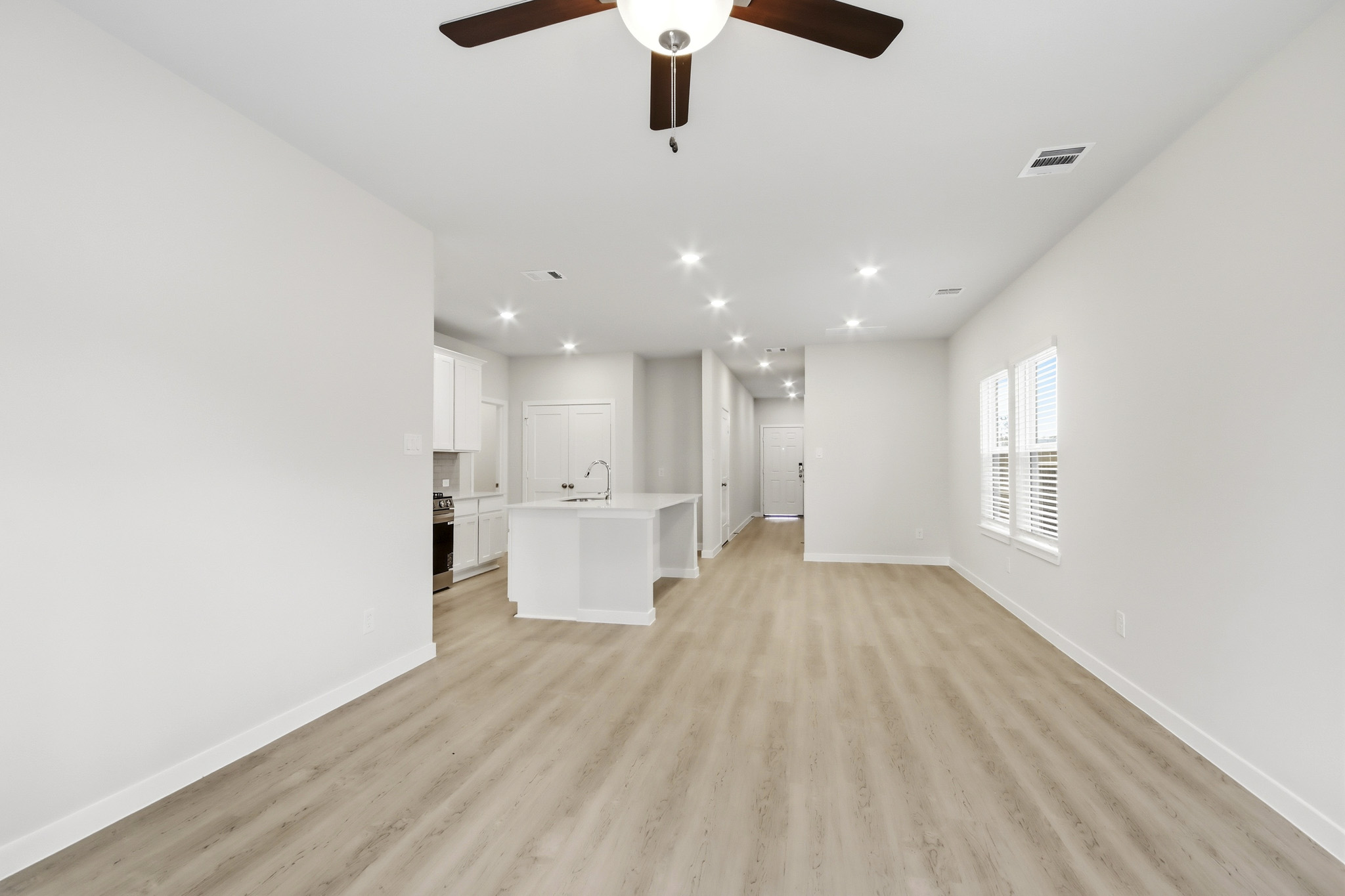 A large empty room with a white countertop and a ceiling fan.