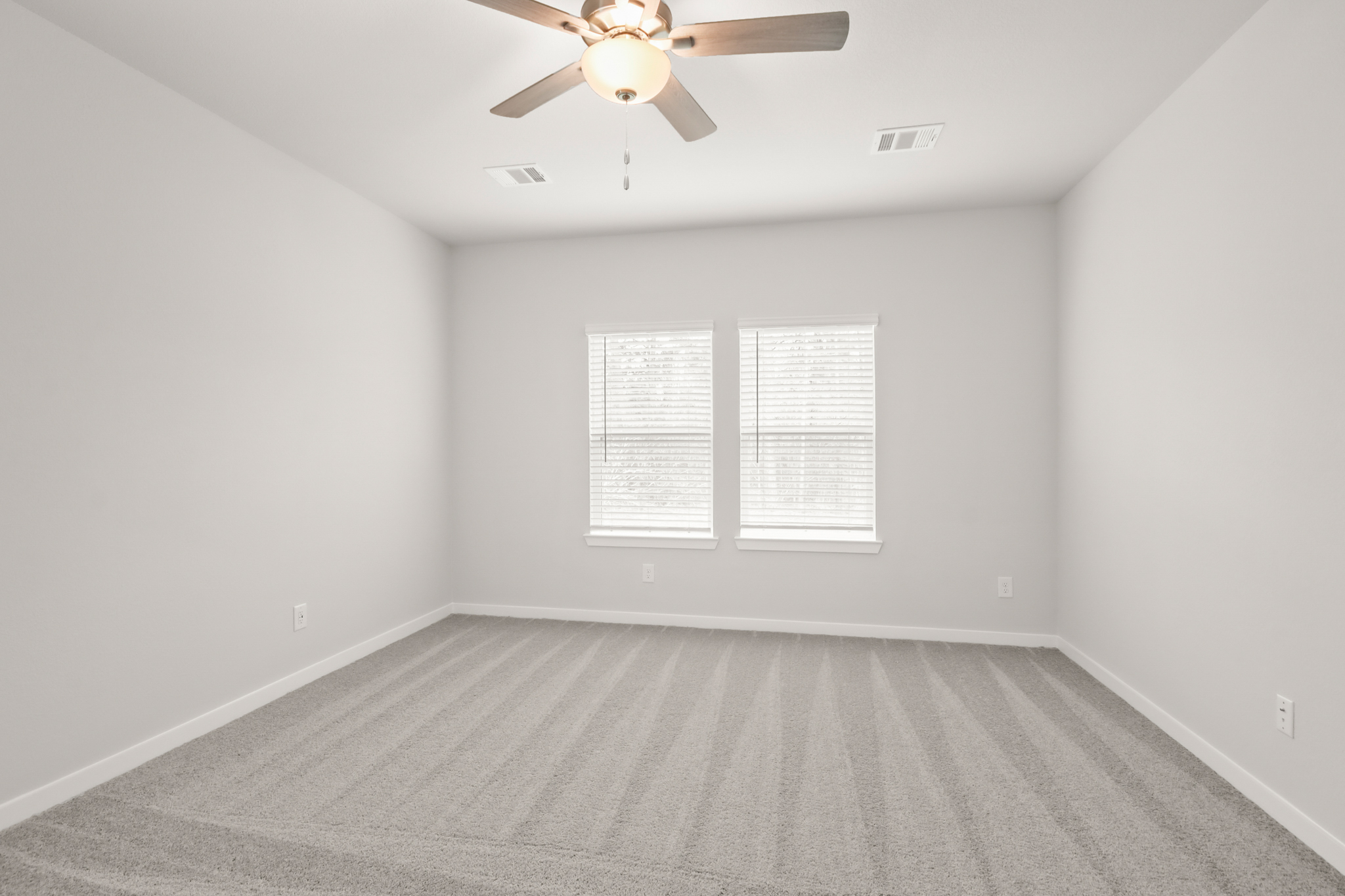 A room with a ceiling fan and a carpet.
