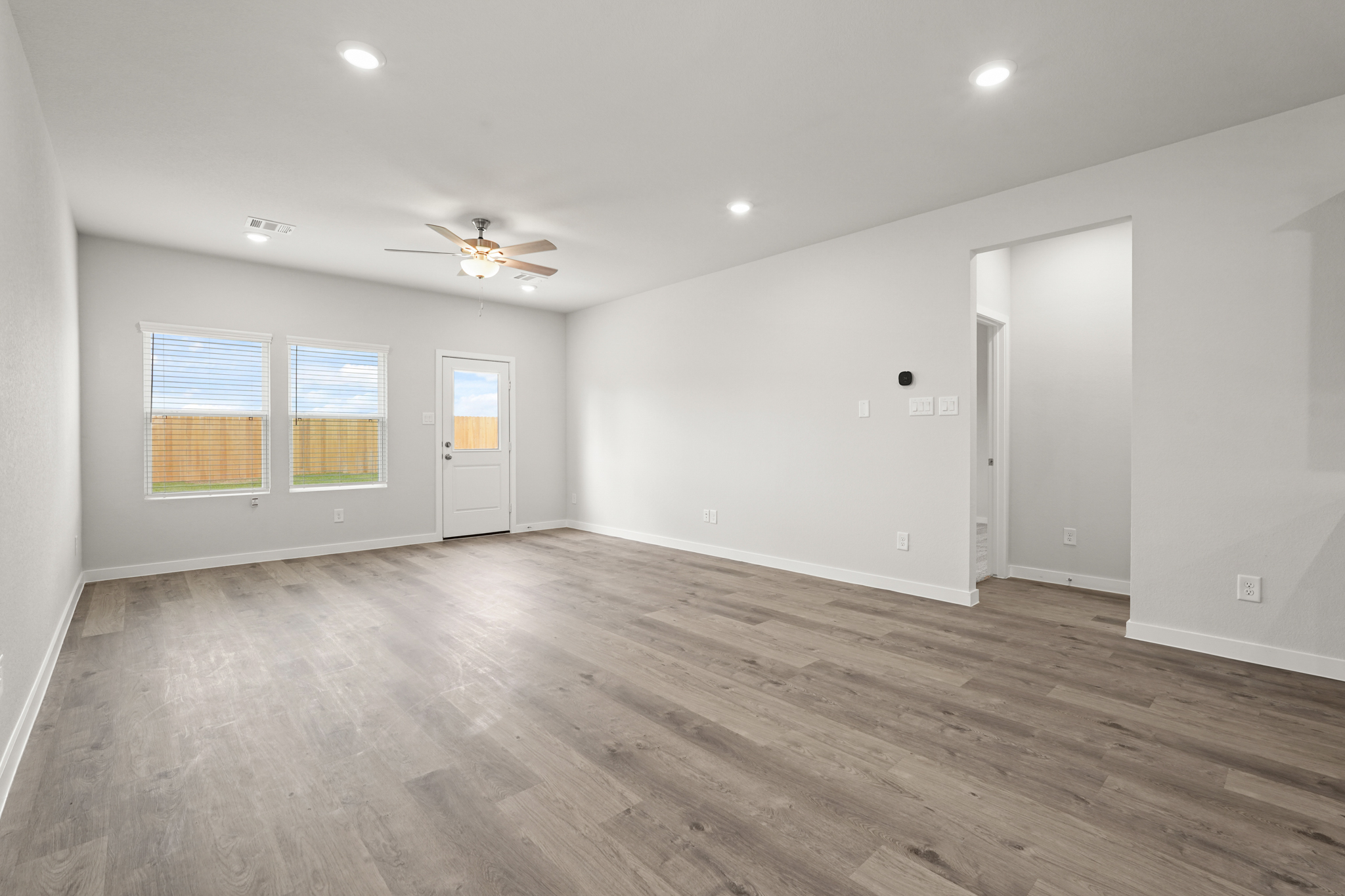 A room with a wood floor and a ceiling fan.
