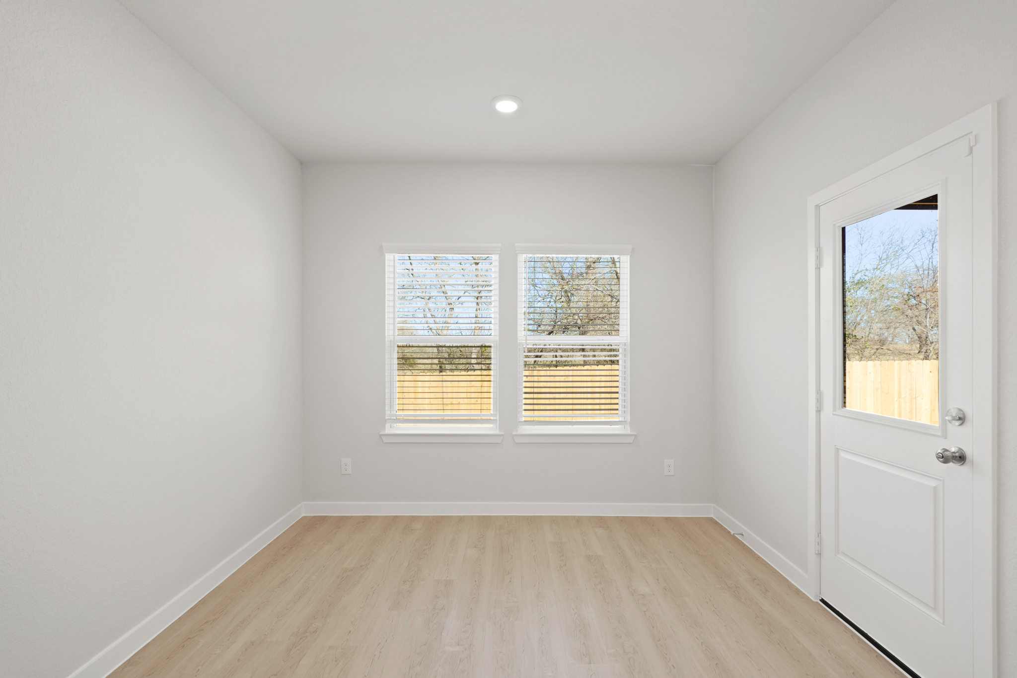 A room with a wood floor and a wood floor with a white door.