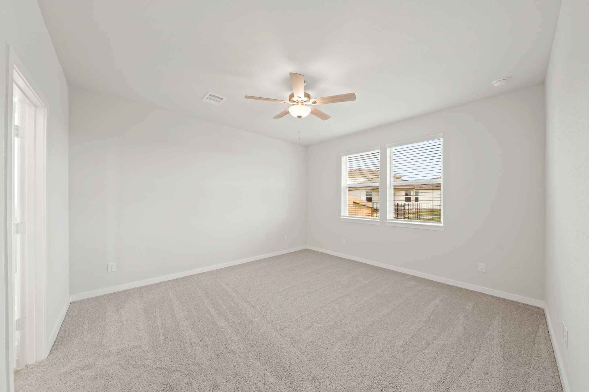 A room with a ceiling fan and a carpet.