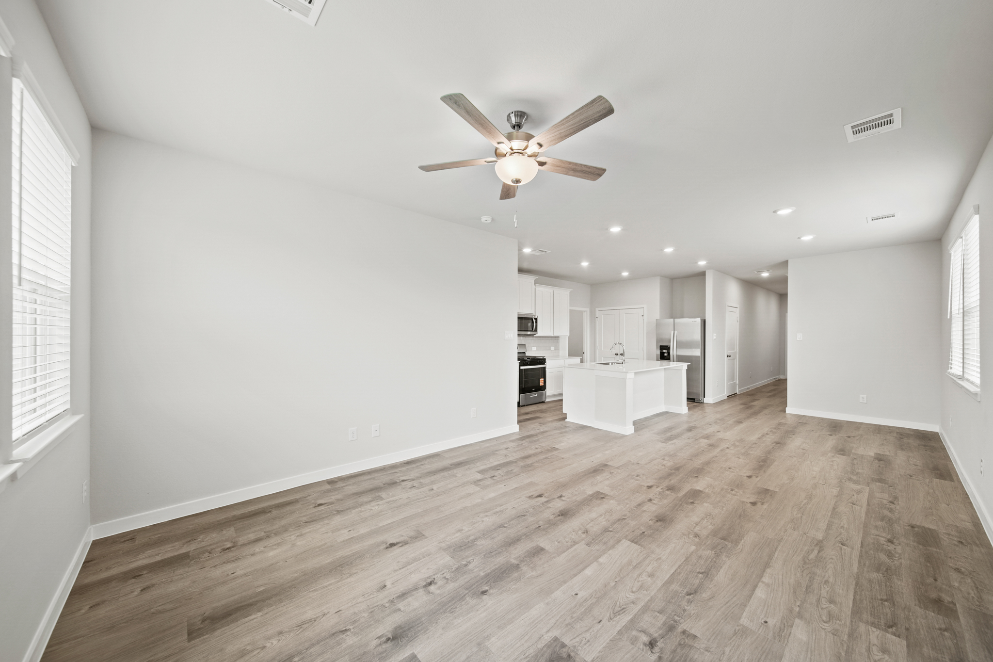 A large empty room with a ceiling fan and a wood floor.