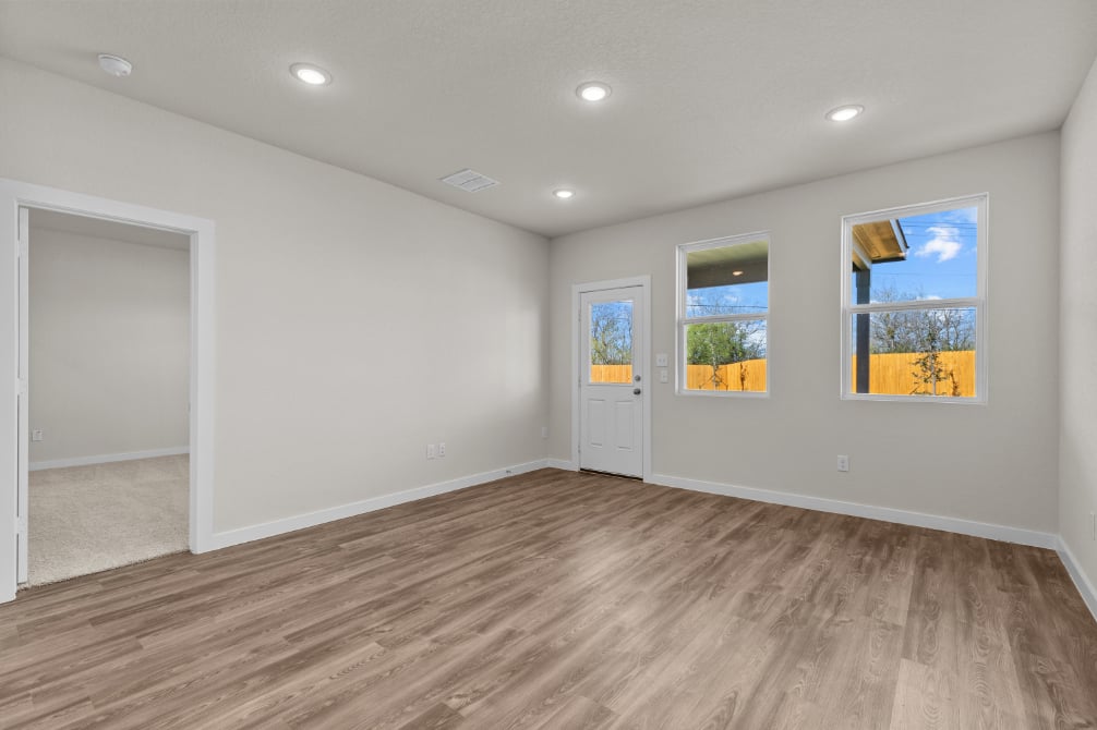 A room with a wood floor and a wood floor with a door and a window with a tree.