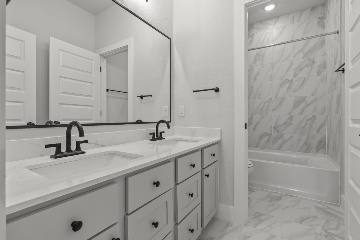 A bathroom with a tub sink and cabinets.