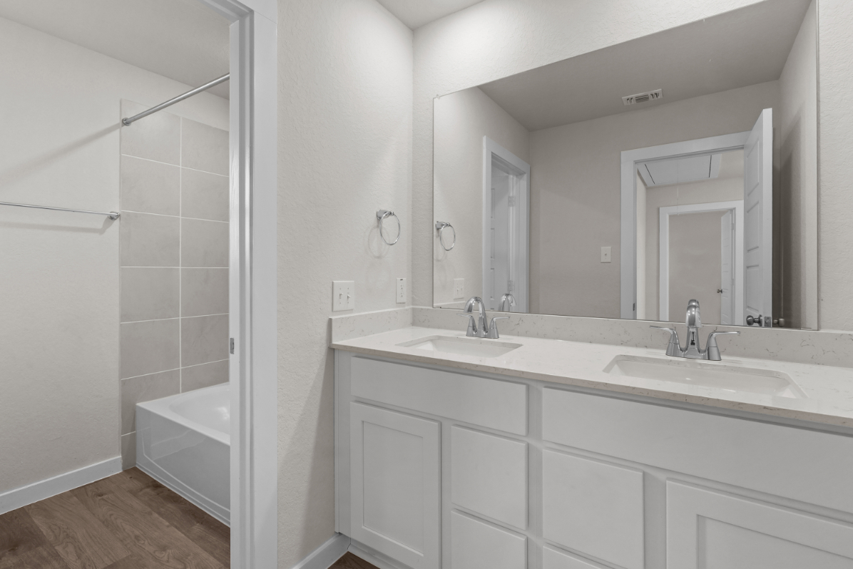 A bathroom with a tub sink and mirror.