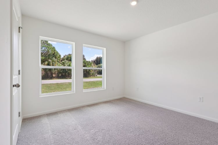 A room with a window and a door with a view of the trees.