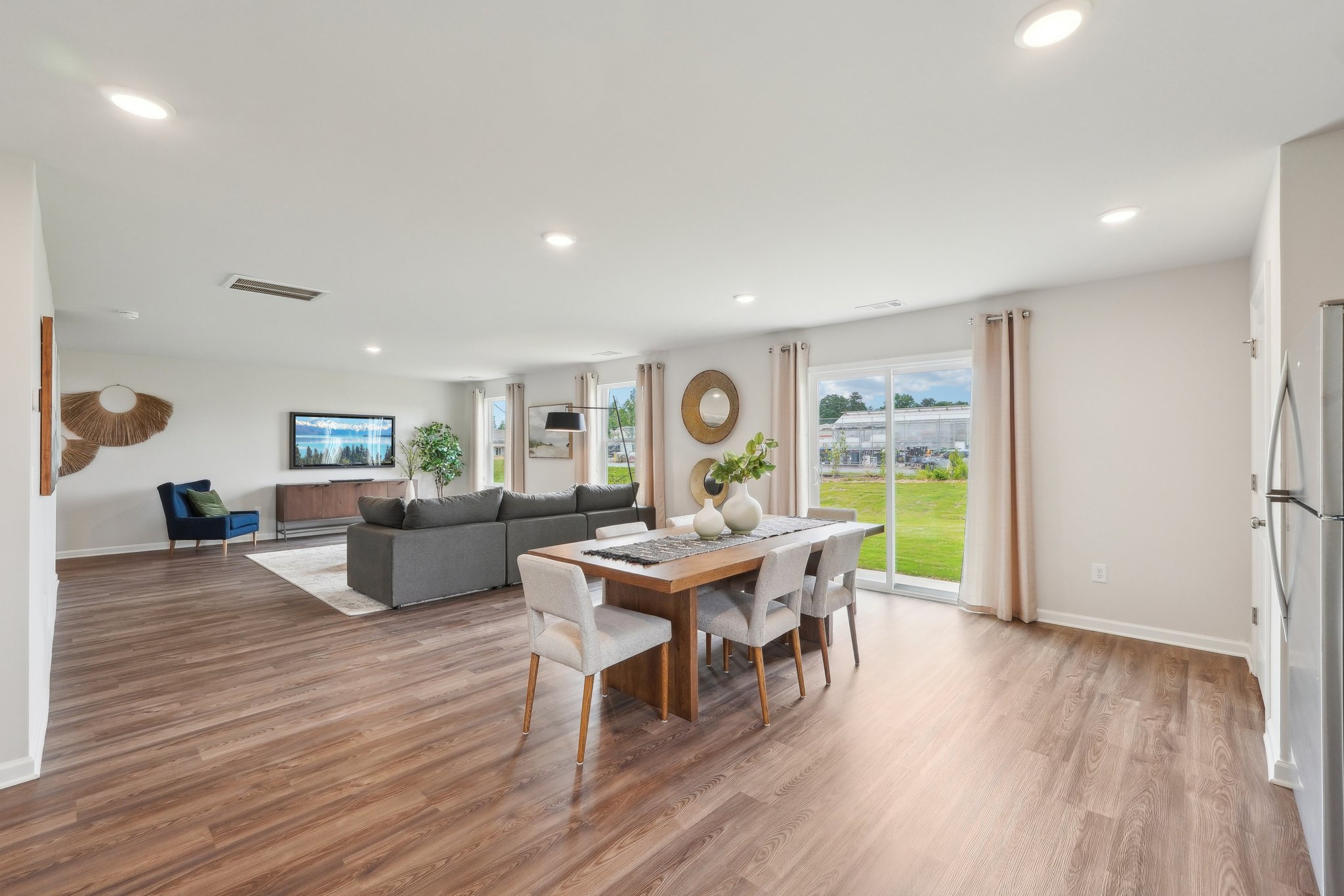 A large living room with a wood floor and a large dining table.